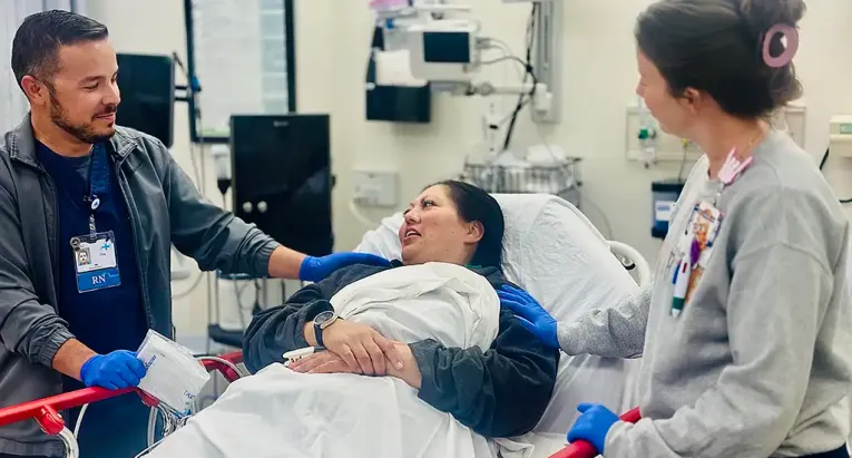Nurses in emergency room at patient bedside consoling adult female patient. 